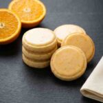 orange-shortbread-cookie-hero-shot-1-stacked-glazed-cookies-on-slate-with-halved-orange