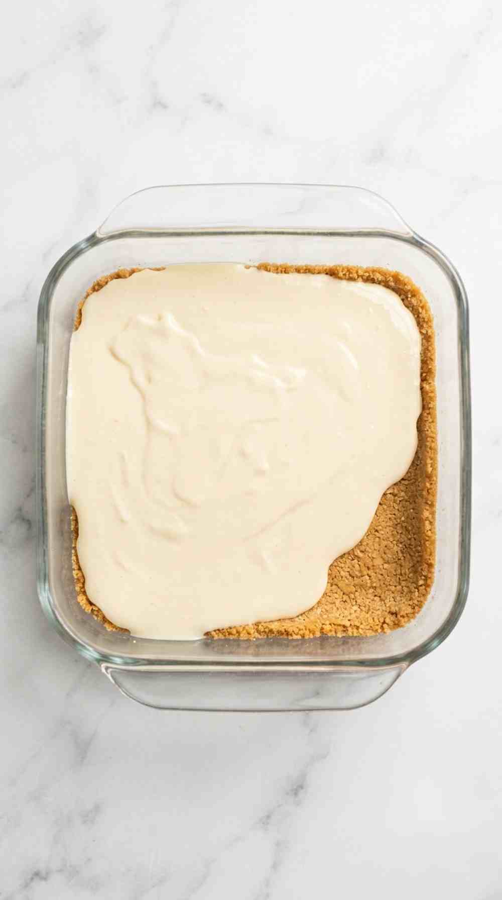 Cheesecake batter poured over the baked graham cracker crust