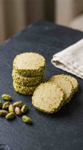 pistachio-shortbread-cookies-hero-shot-1-stacked-cookies-on-dark-slate-with-pistachios